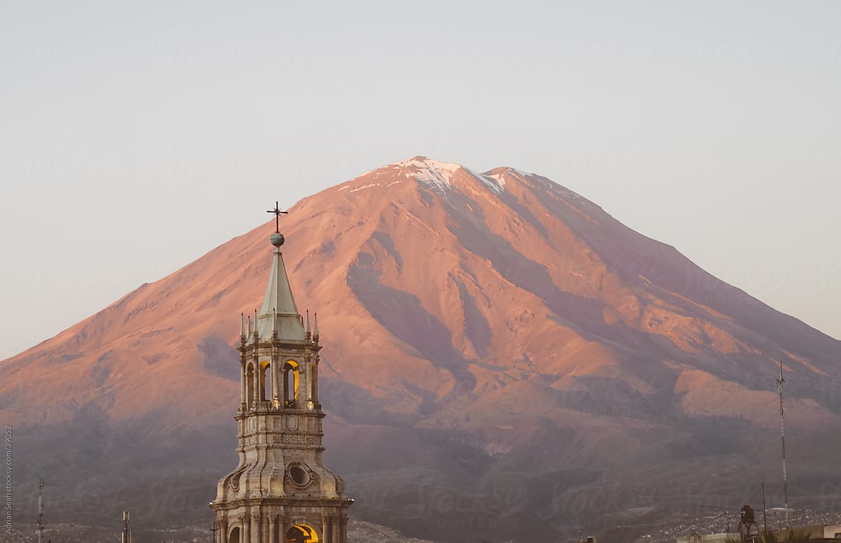 A tower of the Cathedral of Arequipa with the volcano, El Misti, behind in the sunset