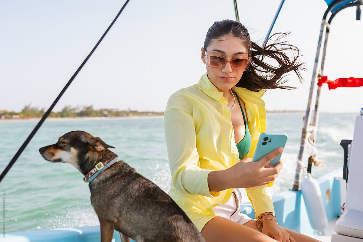 Woman and dog on boat with phone