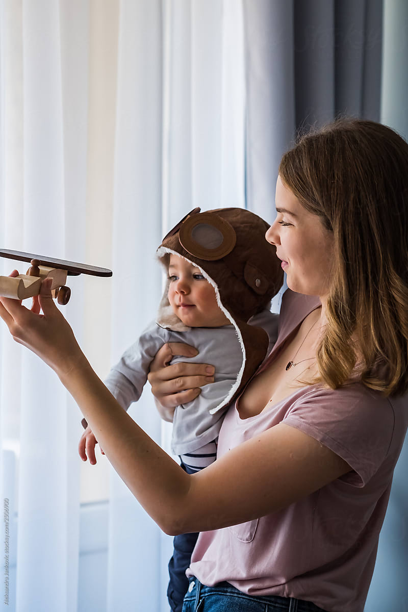 Mother And Baby Playing At Home With Wooden Airplane Toy