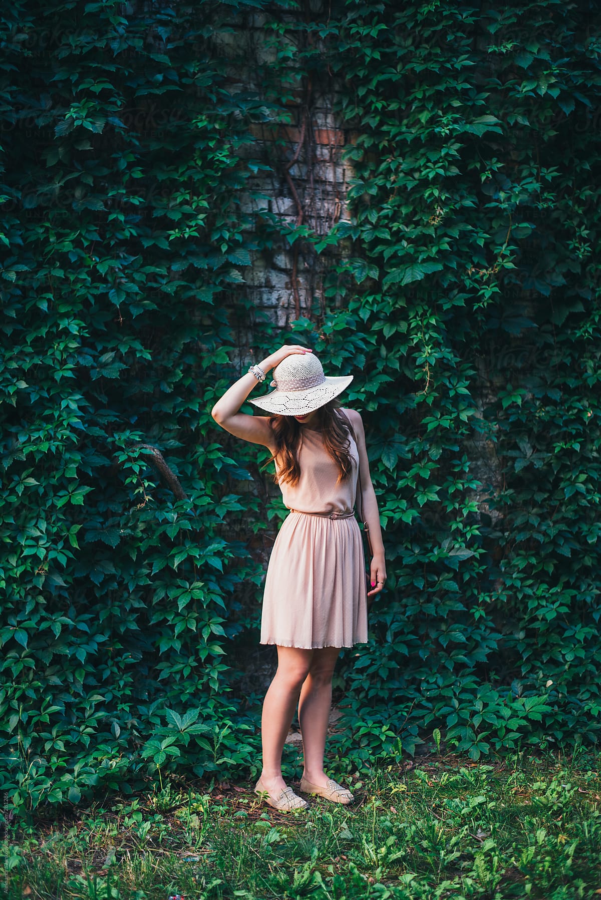 Beautiful Anonymous Woman With Hat Standing In Front Of The Leafy Green Background By Stocksy 