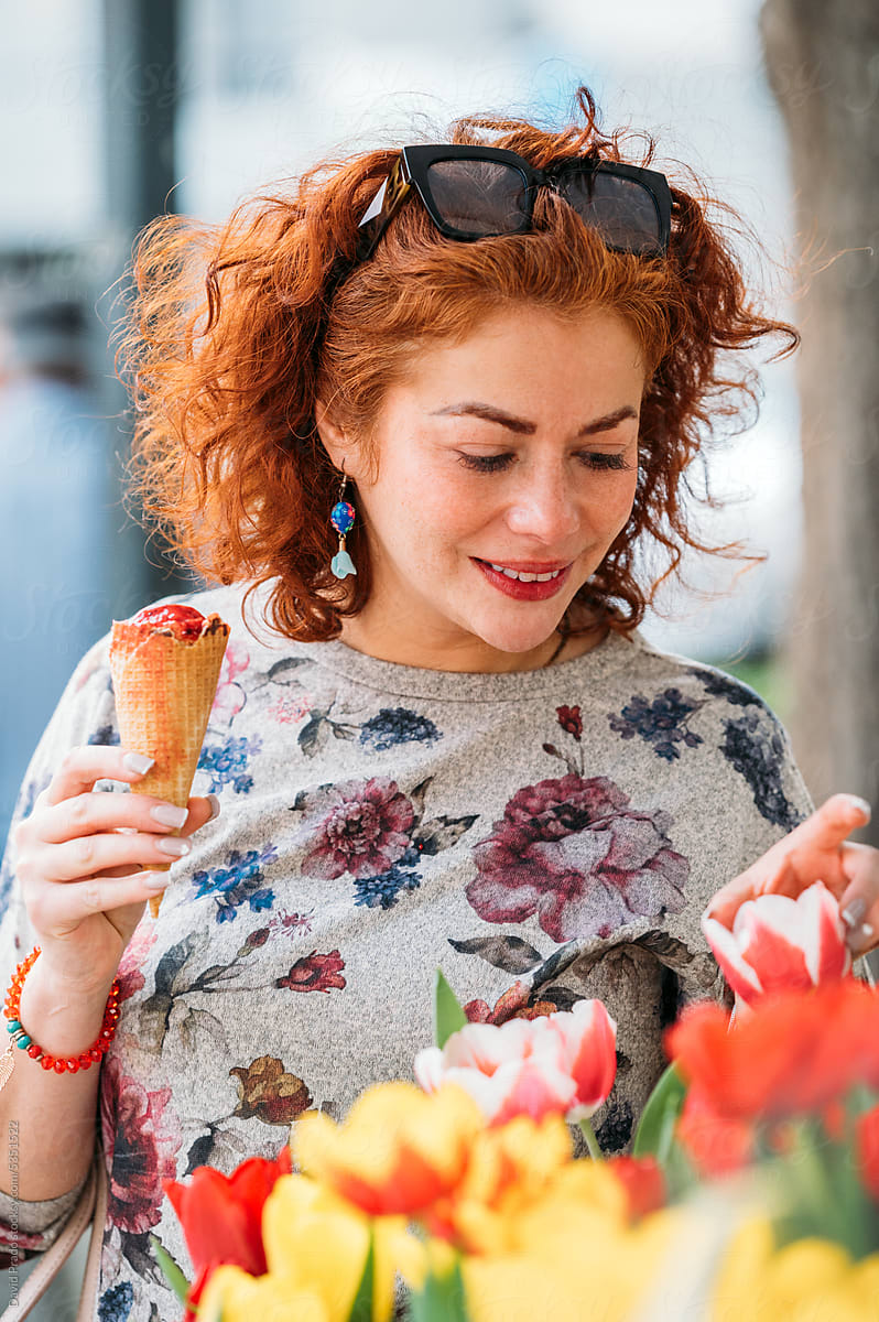 Charming woman with ice cream cone near flowers