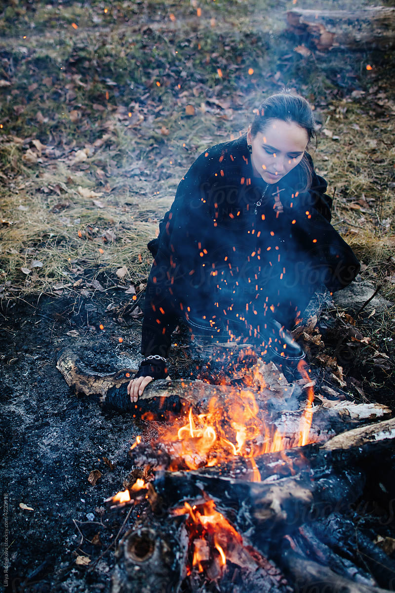 Traveling woman near campfire in forest