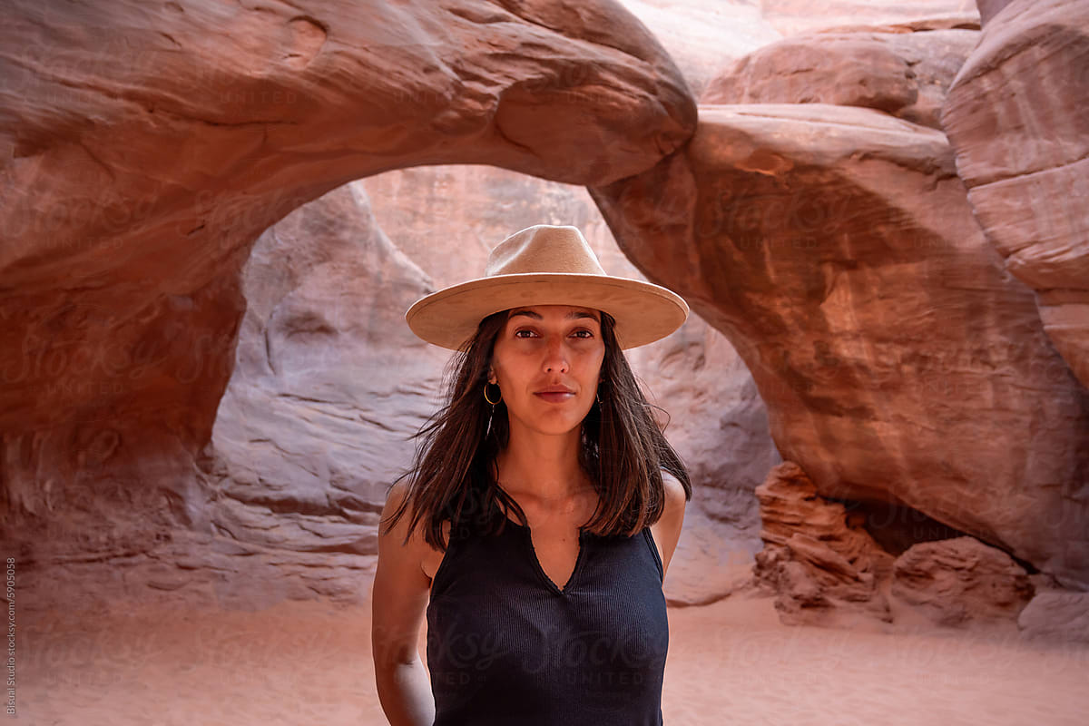 A woman stands below Sand Dune Arch in Arches National park