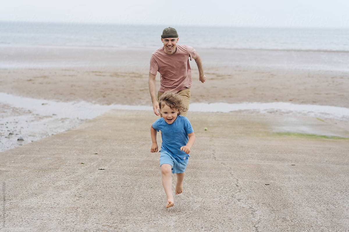 Man running with little boy on the beach