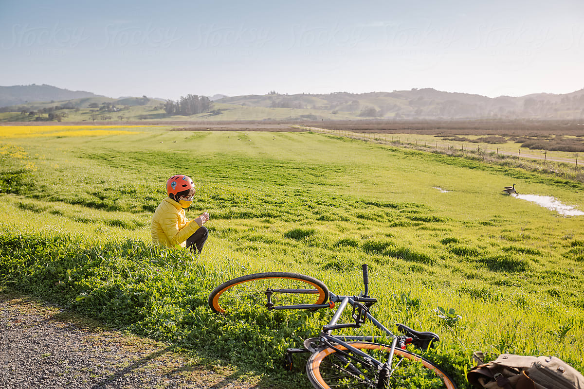 Teen boy sitting on meadow near bike