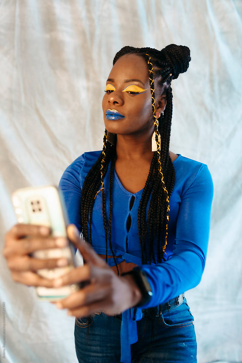 Modern woman with creative makeupand braided hairstyle taking a selfie