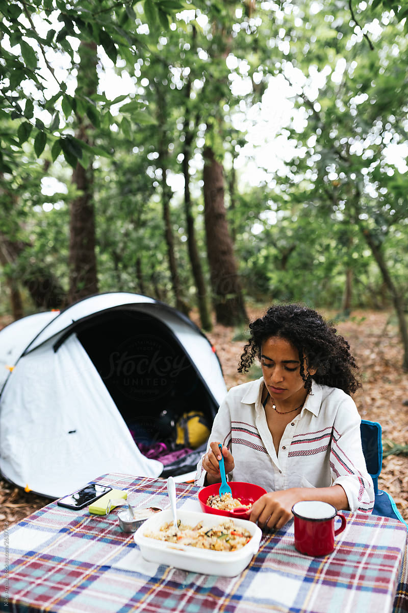 African american woman eating some food on a table outdoor,