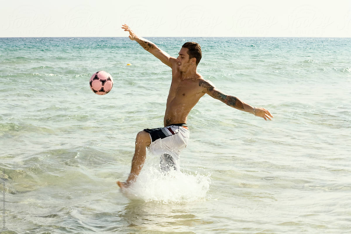 Young man playing soccer in the water