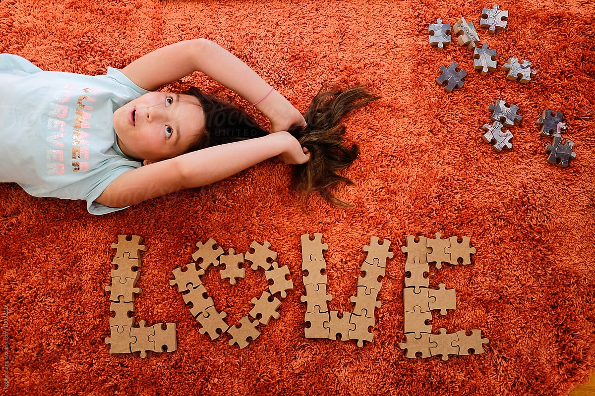 Young girl laying on floor with love spelled in puzzle pieces