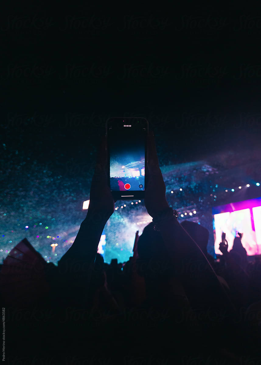 Unrecognizable person in the crowd recording a concert with smartphone
