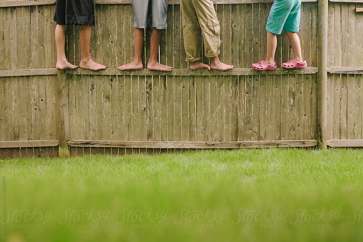 Young friend kids together standing on fence looking at backyard