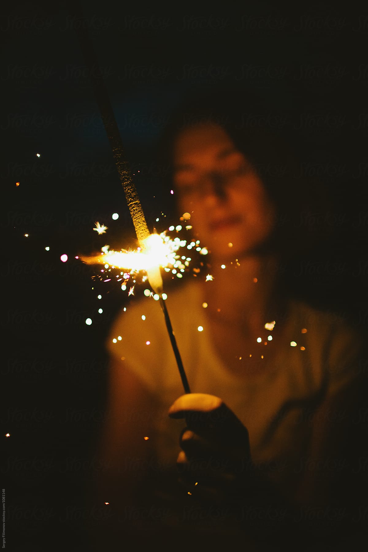 Anonymous woman with sparkler in night