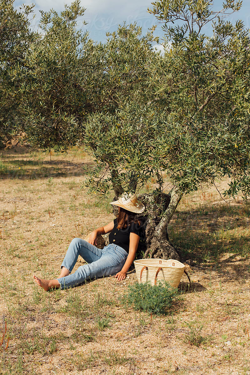 Young woman sitting on the ground under a tree taking a break