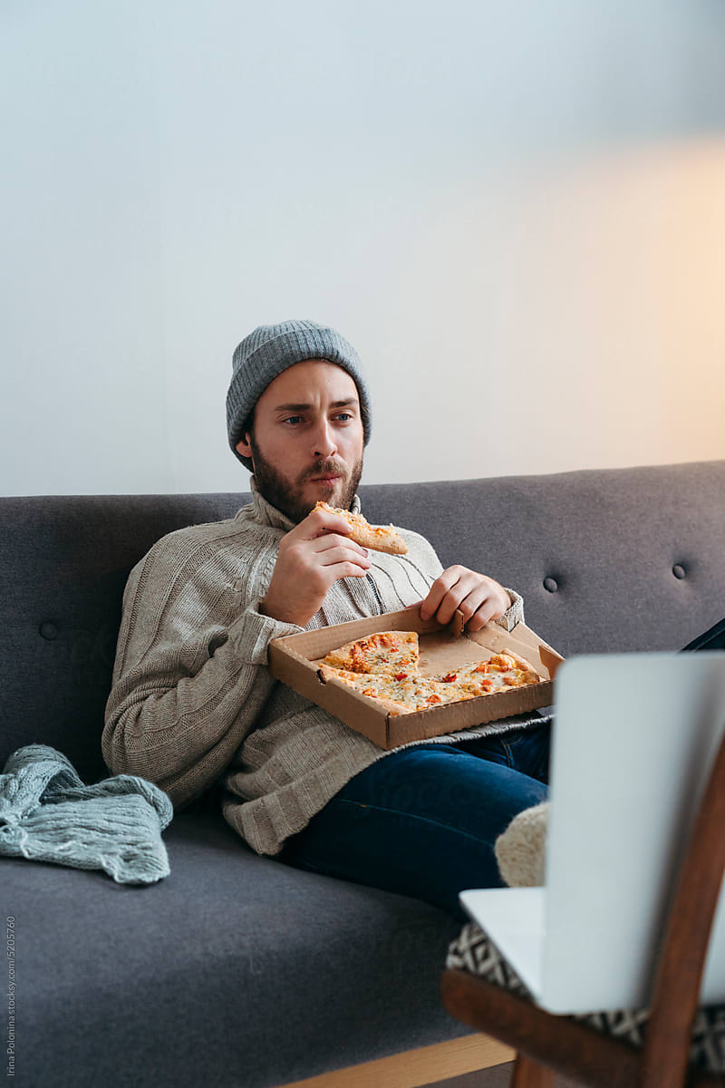 Modern male eats pizza at cozy home.