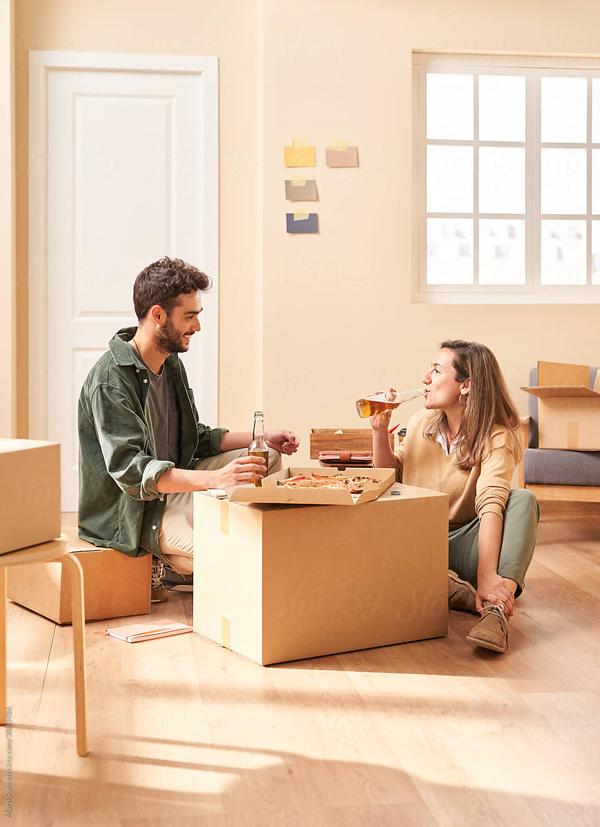 Young man and woman drinking beer and talking in new flat