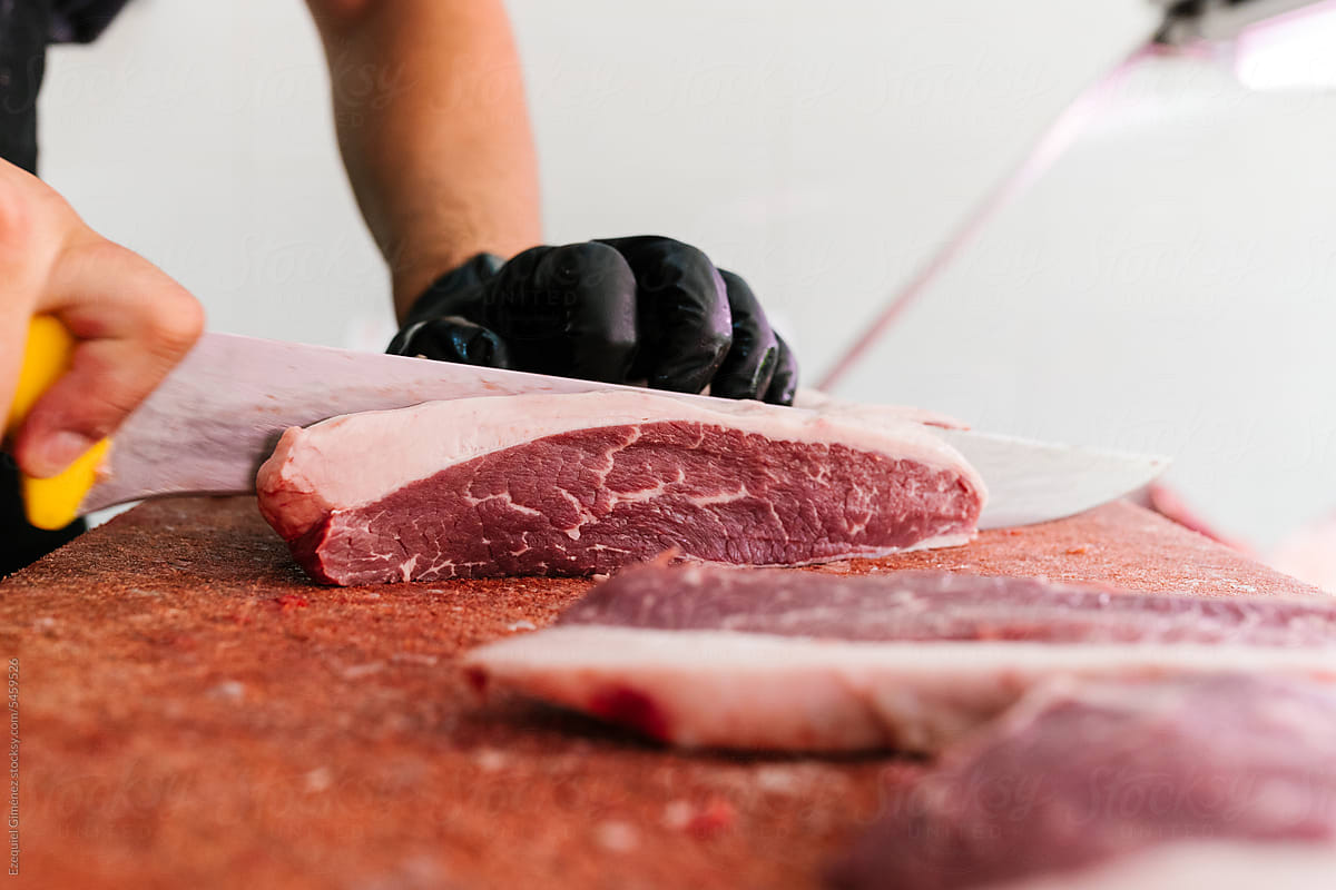 Crop worker slicing red meat in butchery