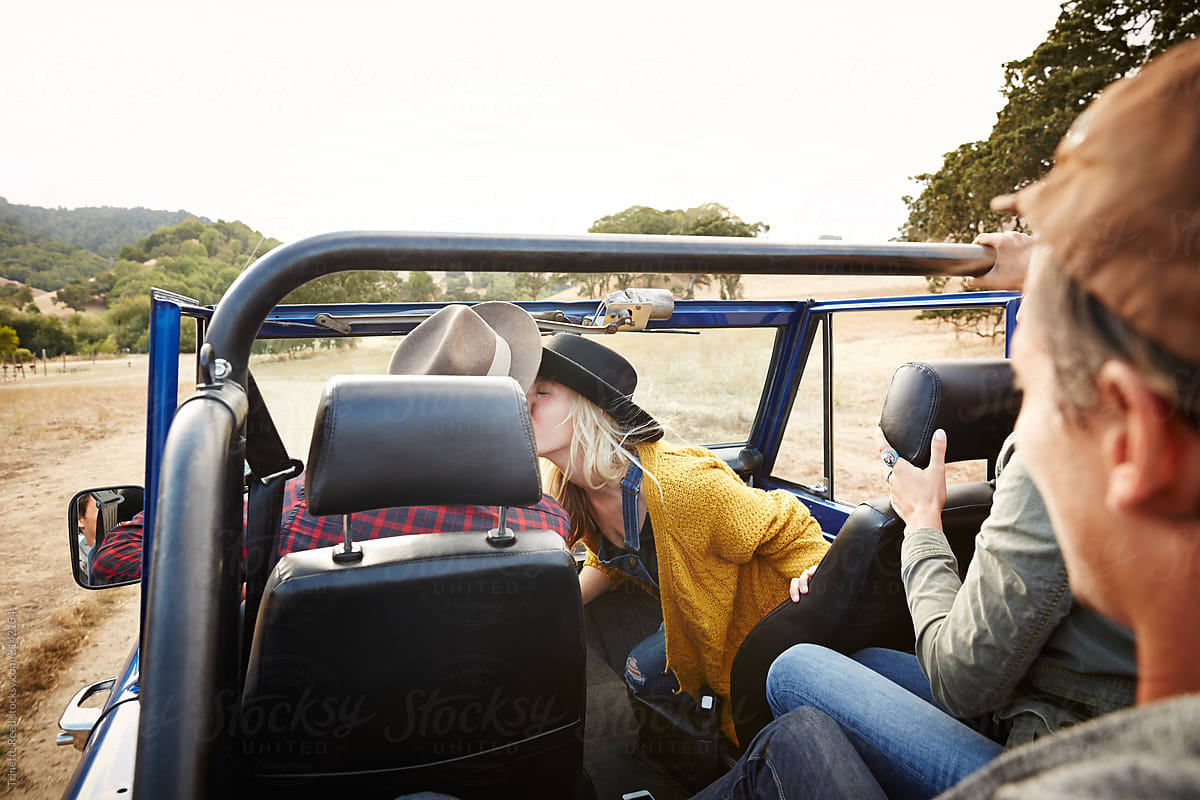 Group of friends on a road trip in nature. Woman is kissing her boyfriend.