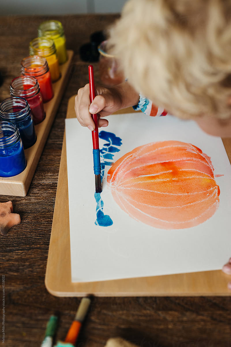 Cute little boy painting a pumpkin