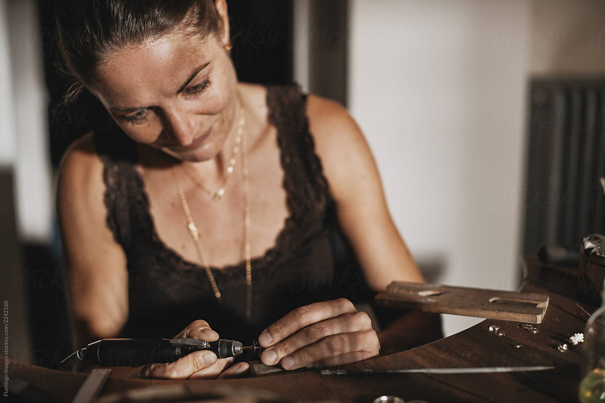 Female jeweler using an engraver at a studio workbench