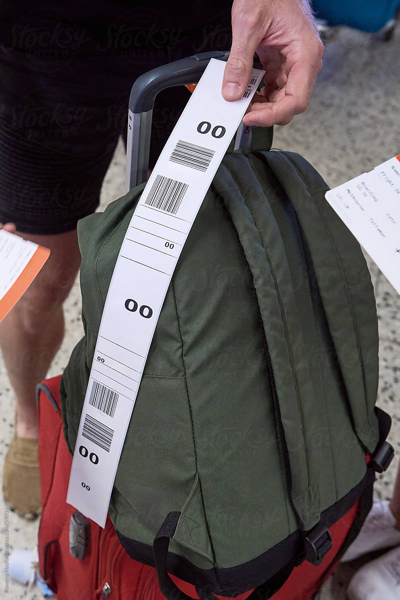 Passenger attaching baggage ticket from self check-in machine