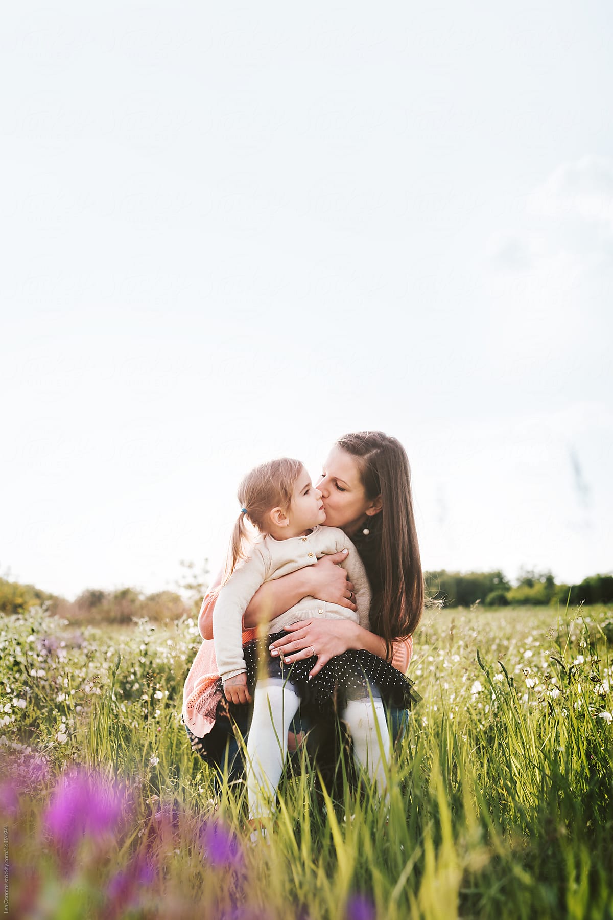 Mother Kissing Her Cute Daughter While Playing On A Summer Field By Stocksy Contributor Lea
