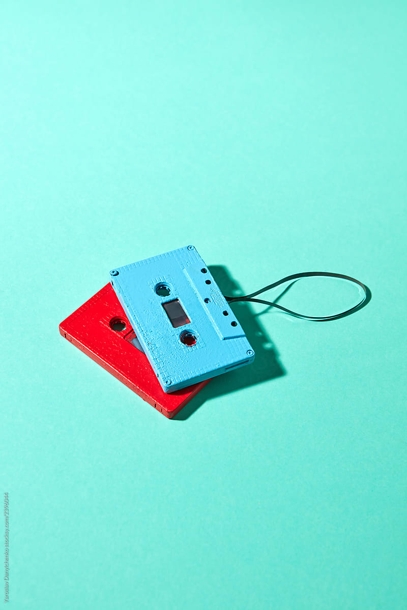 Red and blue retro cassette tapes with shadows on a turquoise color pantone background, copy space. Trend of minimalism.