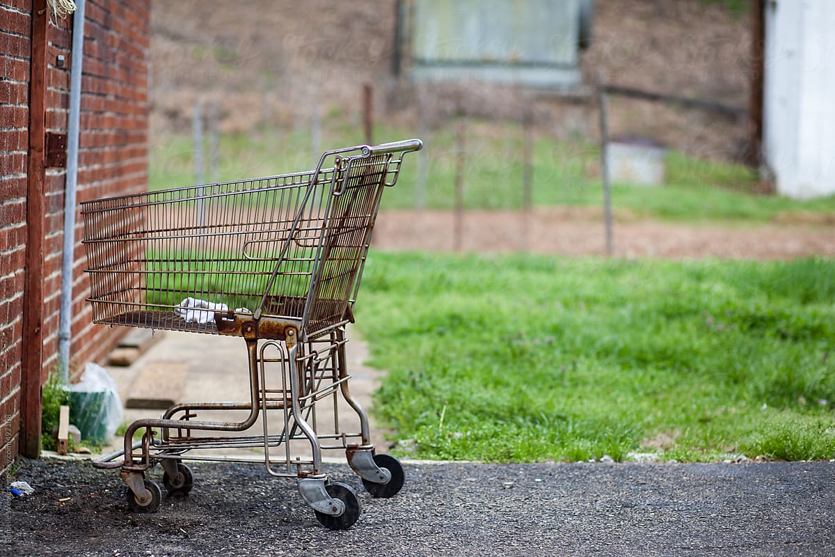 Abandoned shopping cart near patch of grass