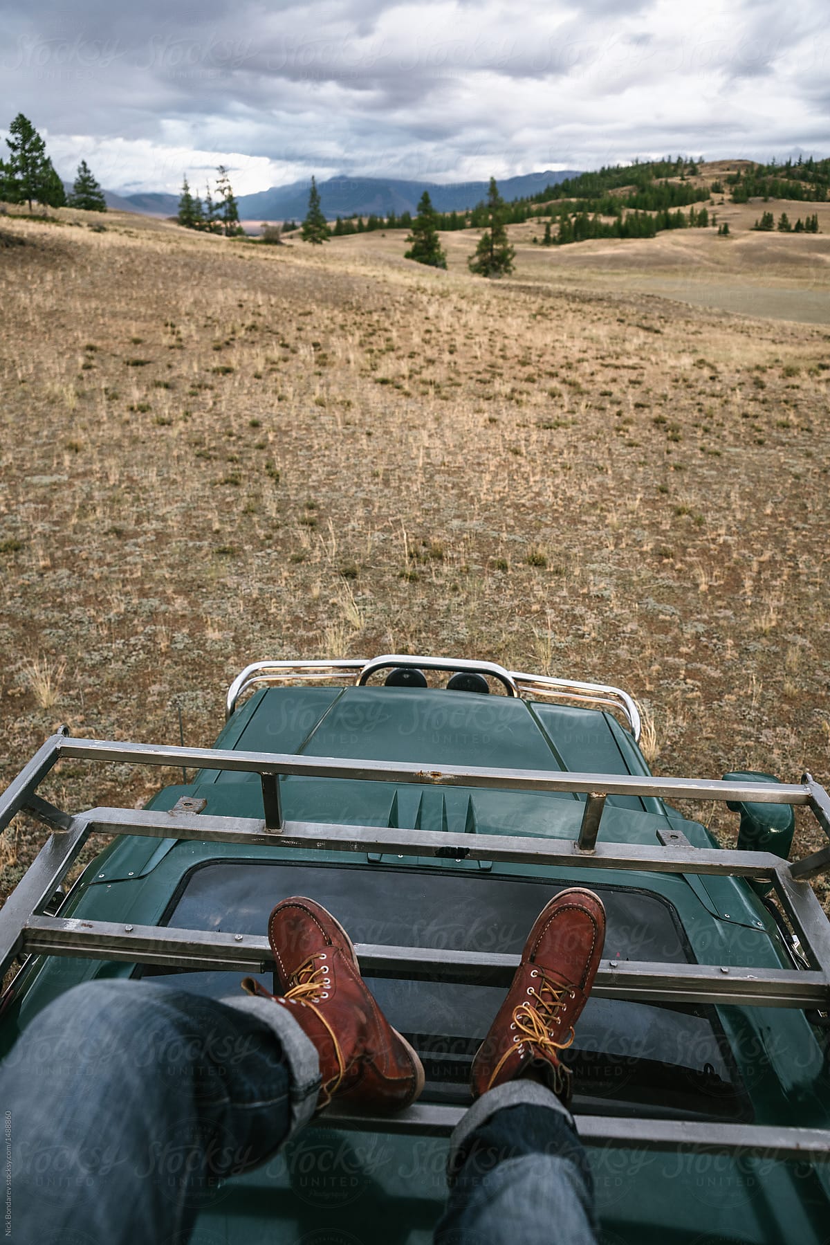 Pov image of anonymous male feet on old jeep parked in the wild area