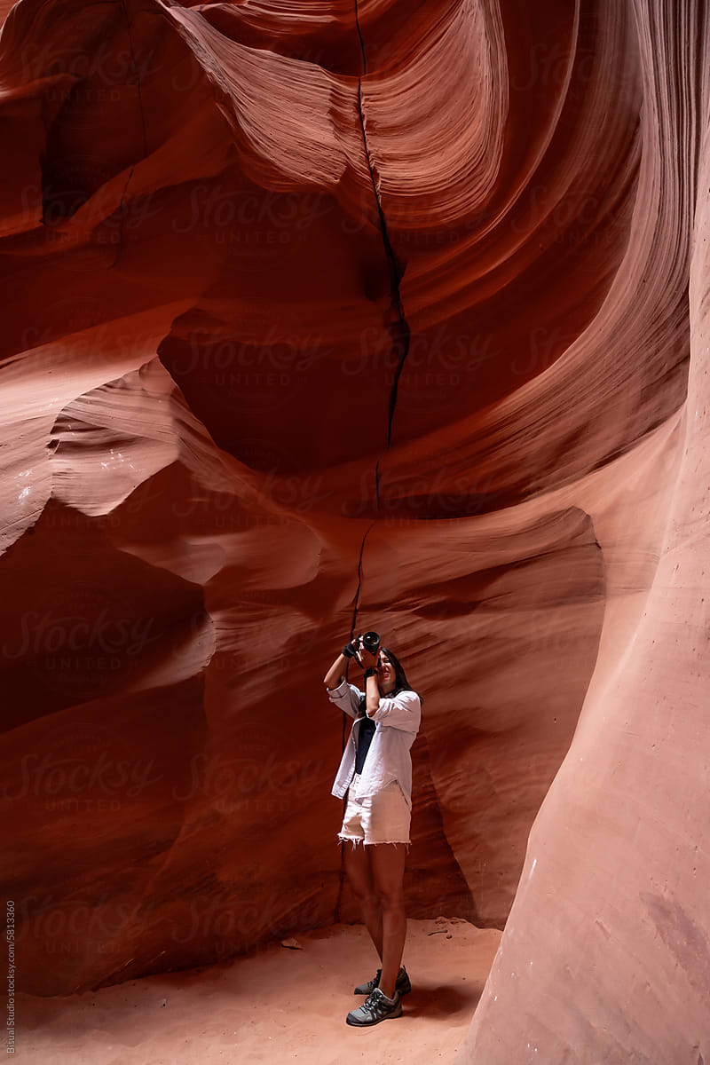 Woman taking photos inside a narrow rock canyon in Arizona