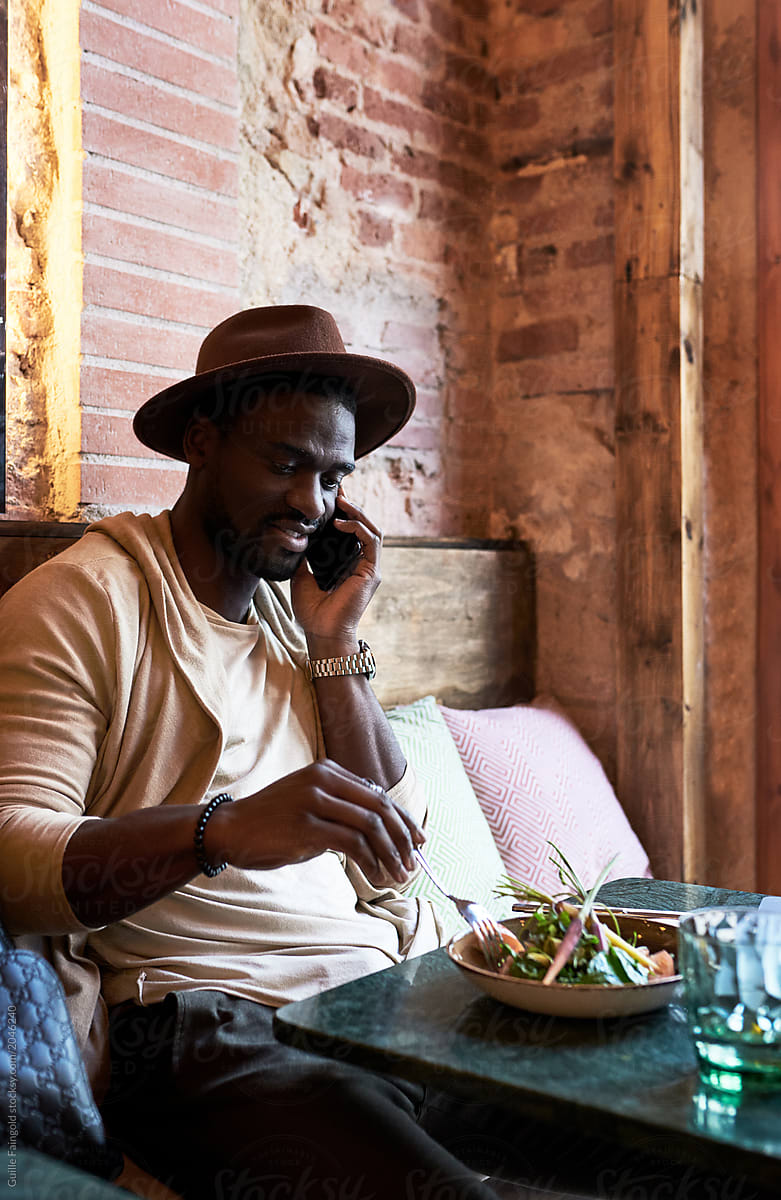 Stylish black speaking on phone in restaurant