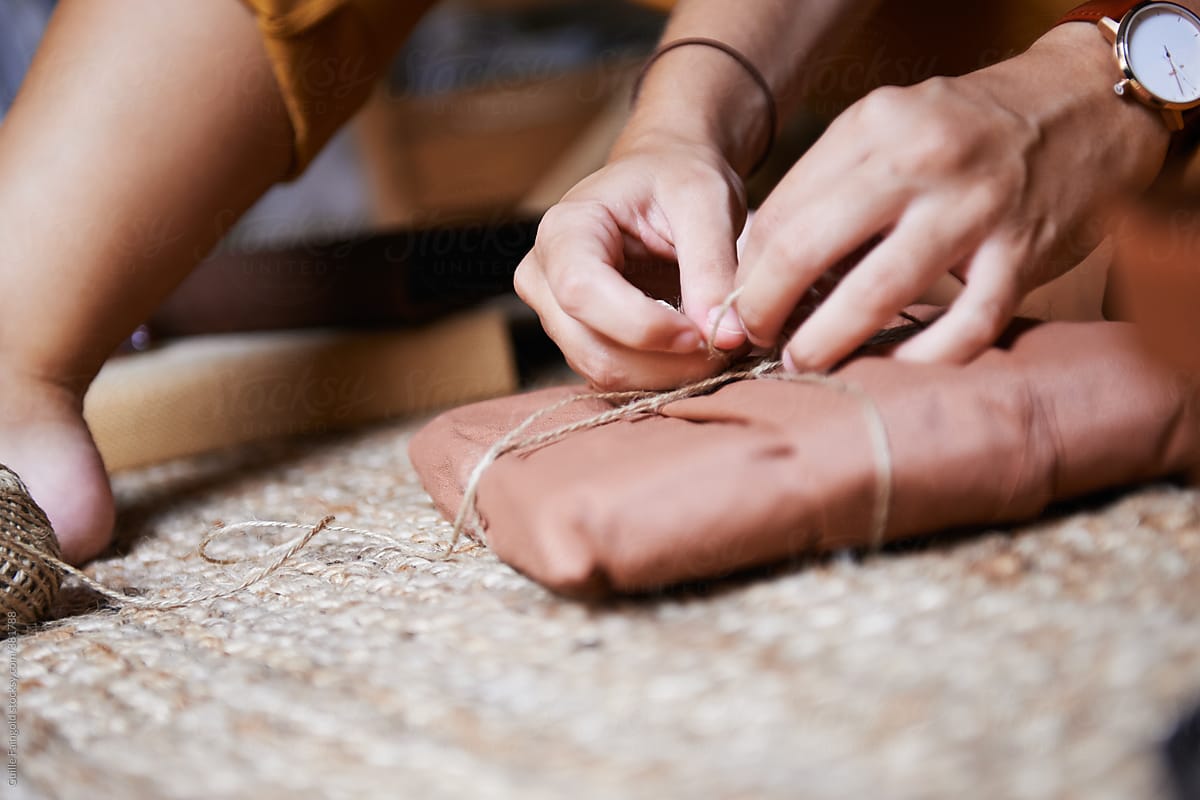 Female hands tying twine on craft paper package