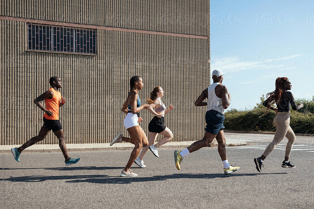 Diverse sportspeople jogging near warehouse