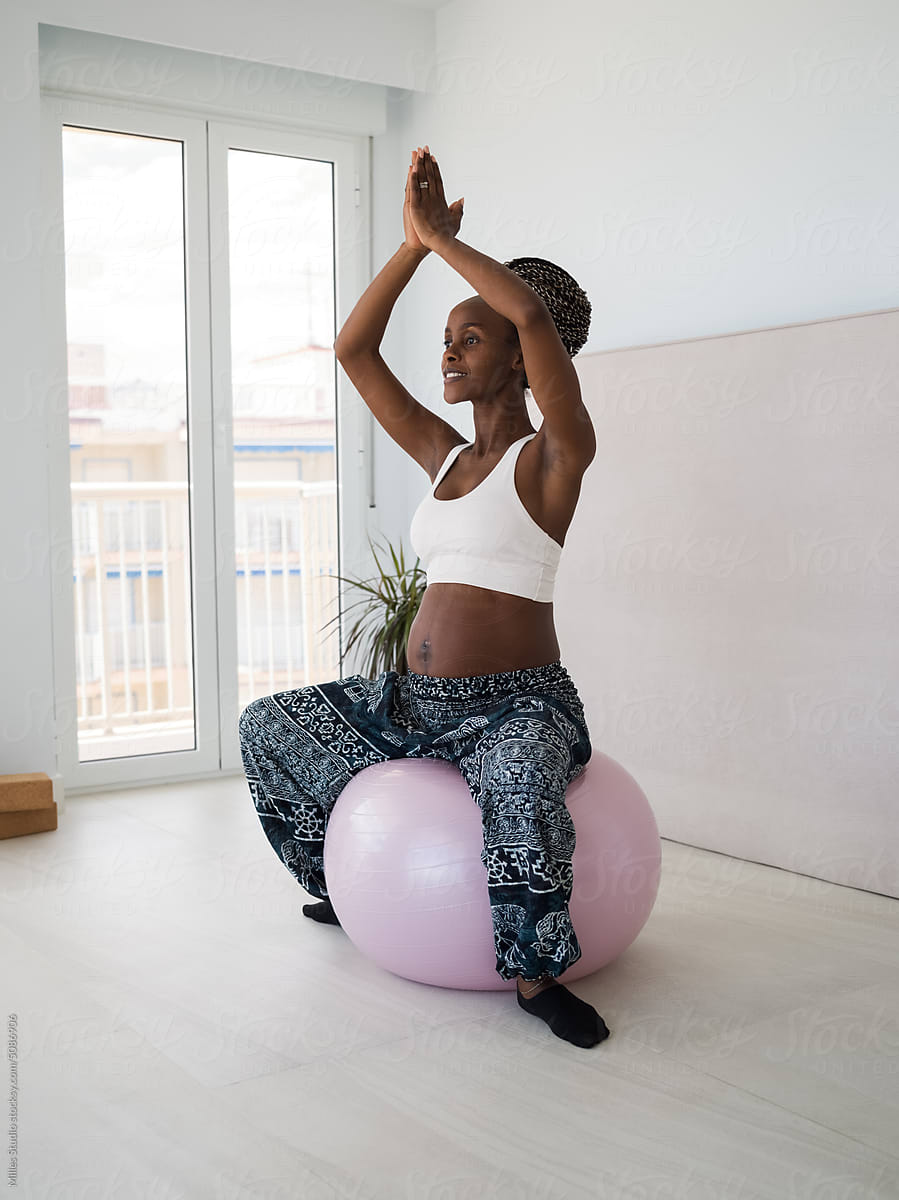 Black lady expecting baby meditating on fit ball