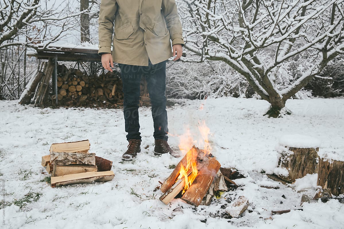 Man warming up next to a bonfire in the snow