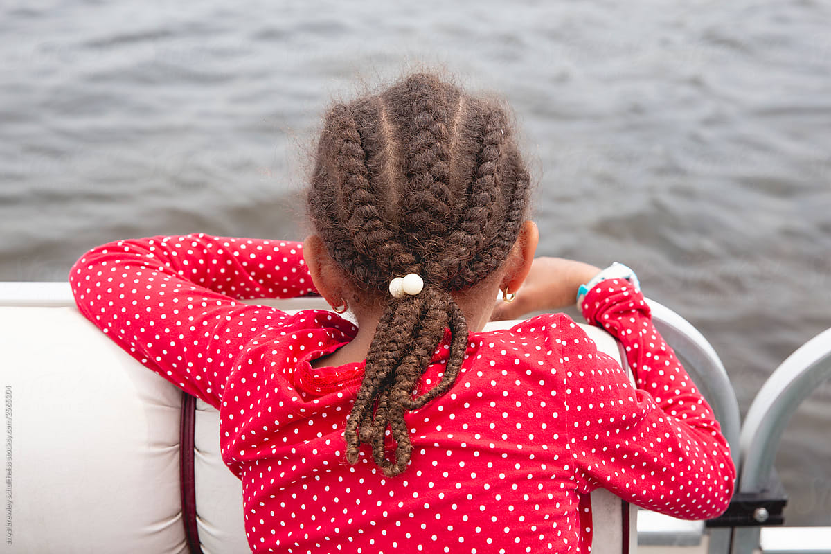 Child with long braids looking over the side of a boat