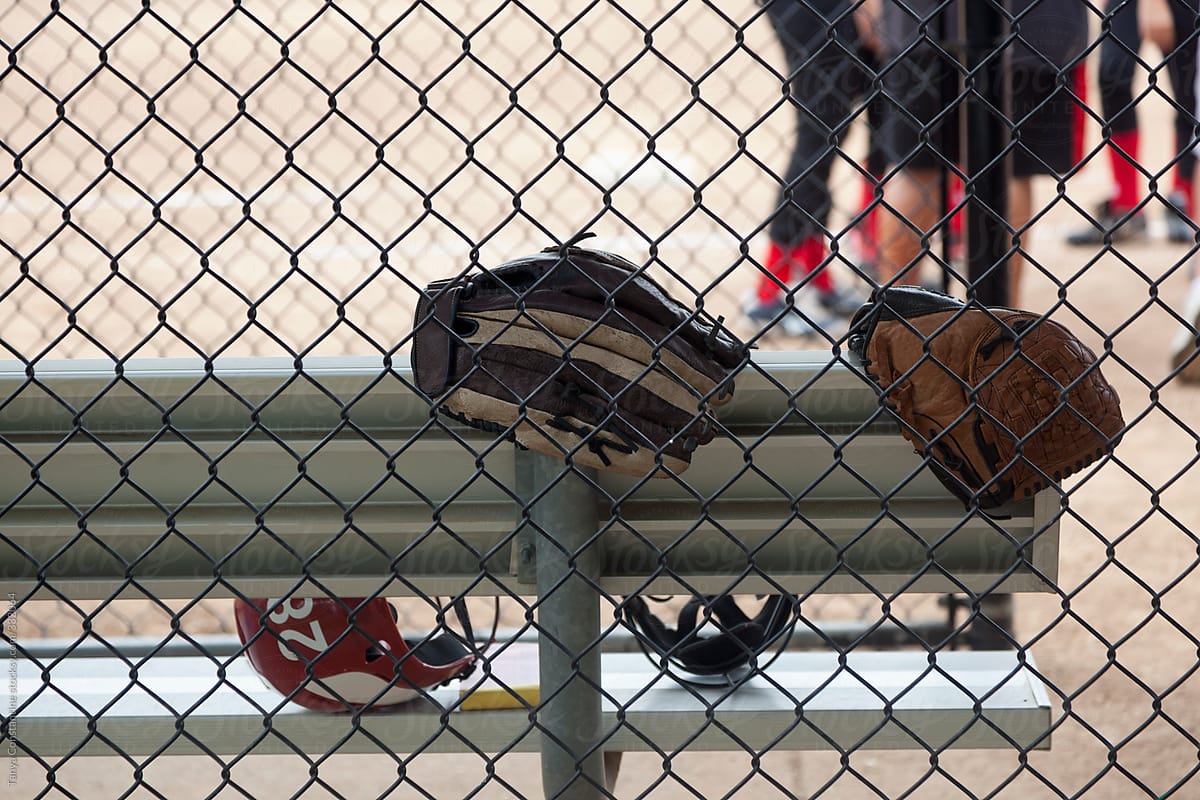 mitts  and helmets laying on bench at softball practice