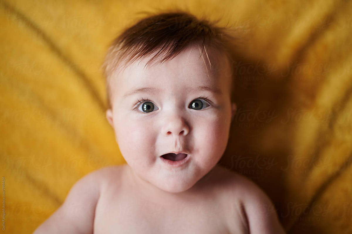 Cute baby with open mouth on yellow.