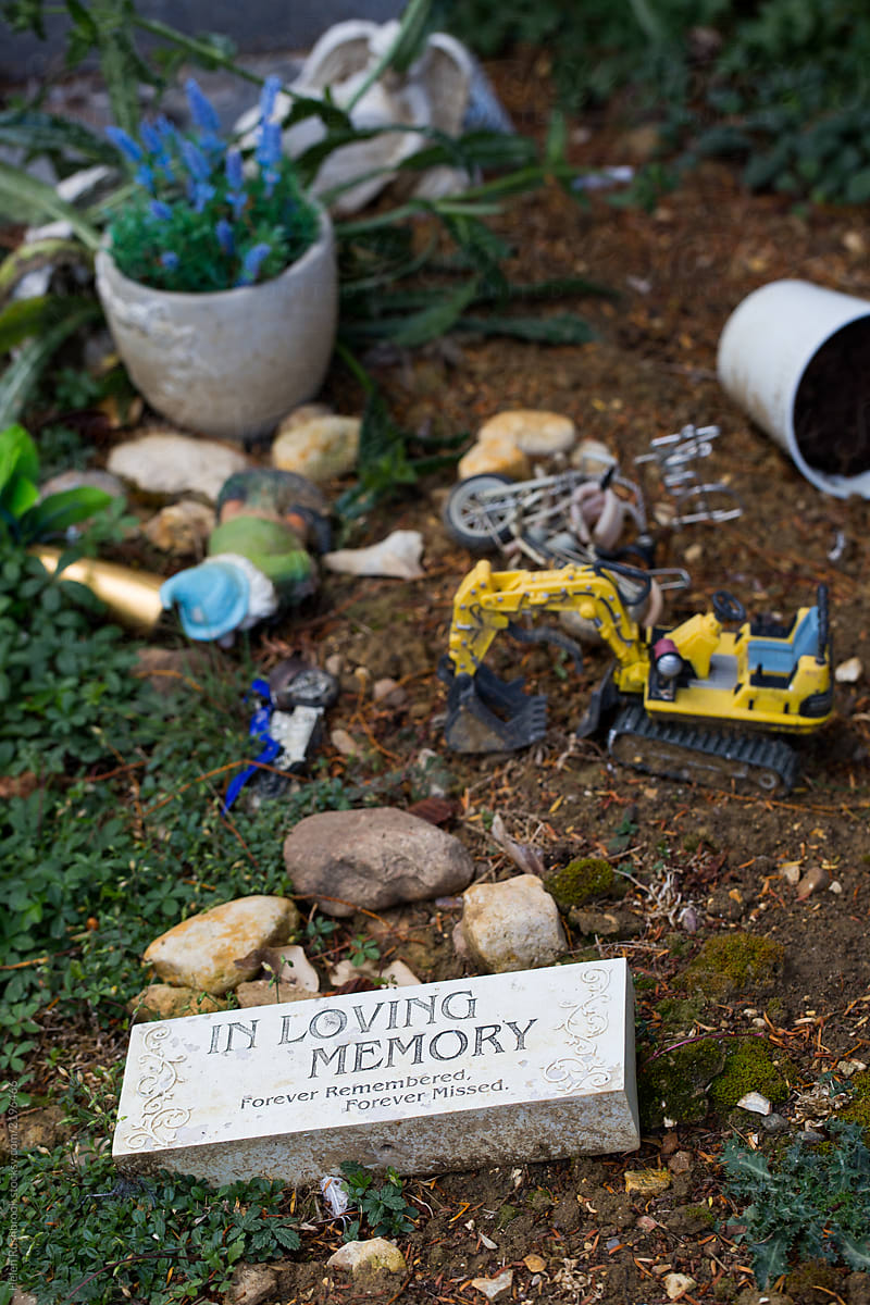 In Loving Memory. Small memorial on a grave plus a collection of random items and toys.