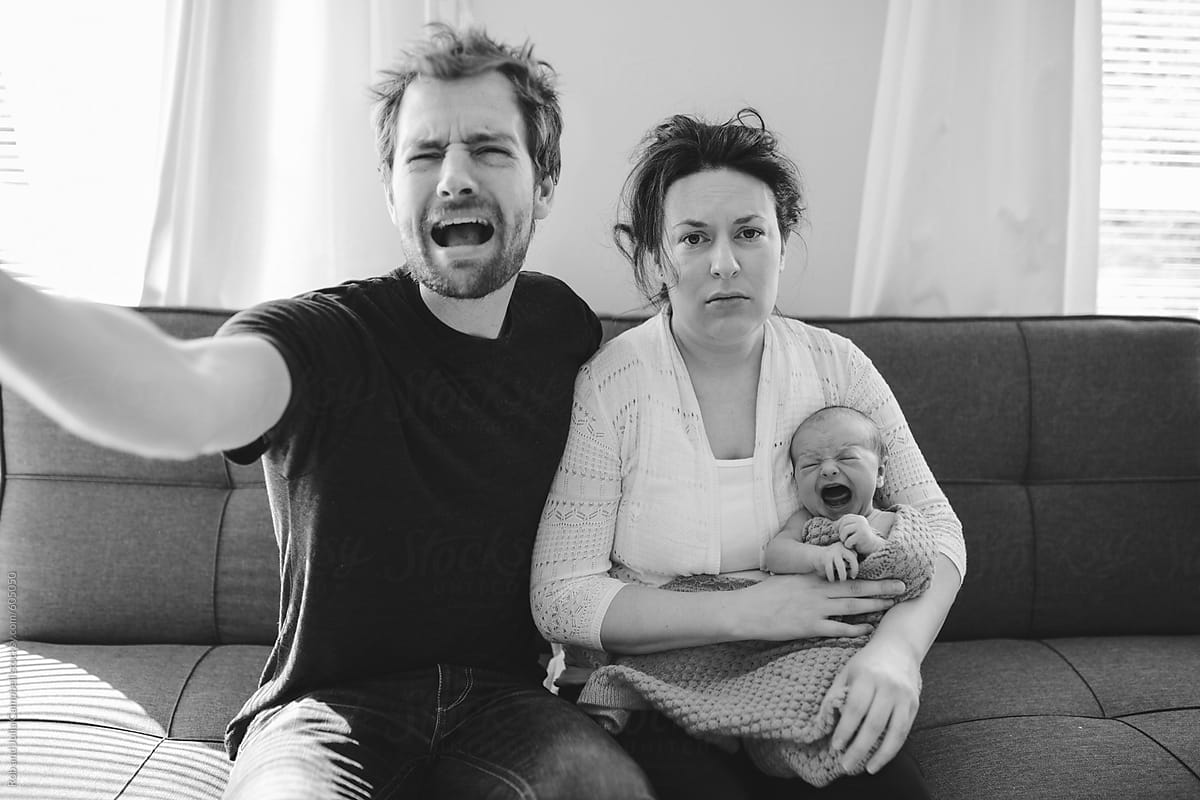 Stressed and tired new parents with screaming newborn baby por Rob and  Julia Campbell - Stocksy United