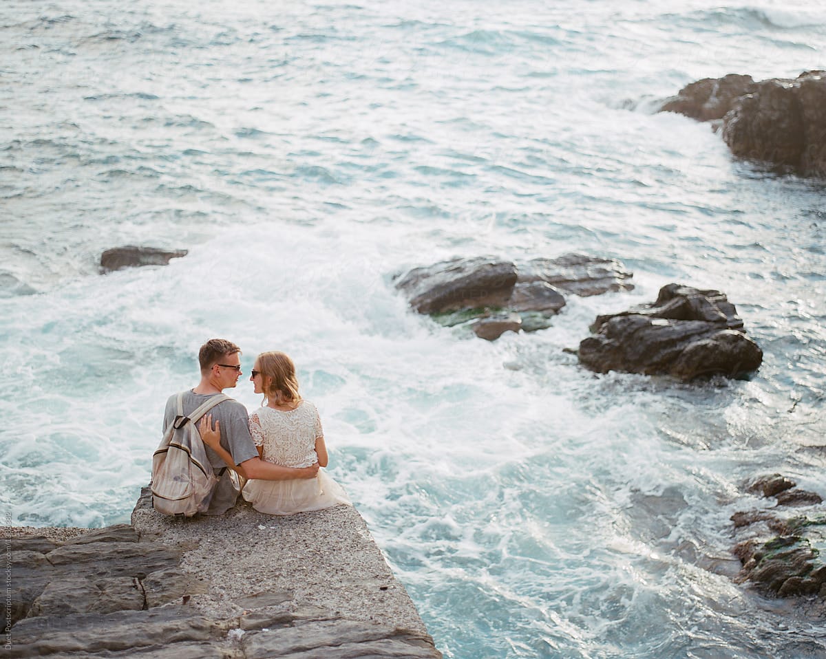 Couple sitting on rocky coast