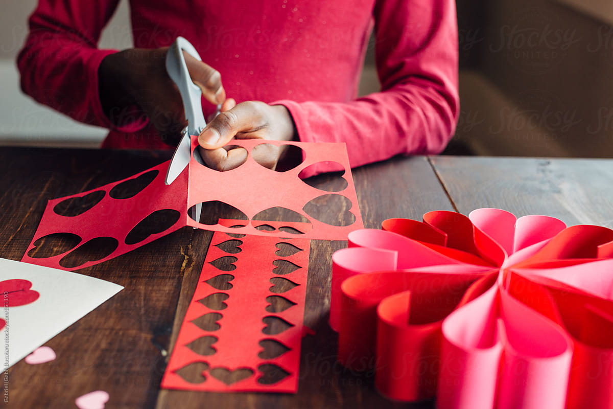 Black girl cutting red paper for Valentines