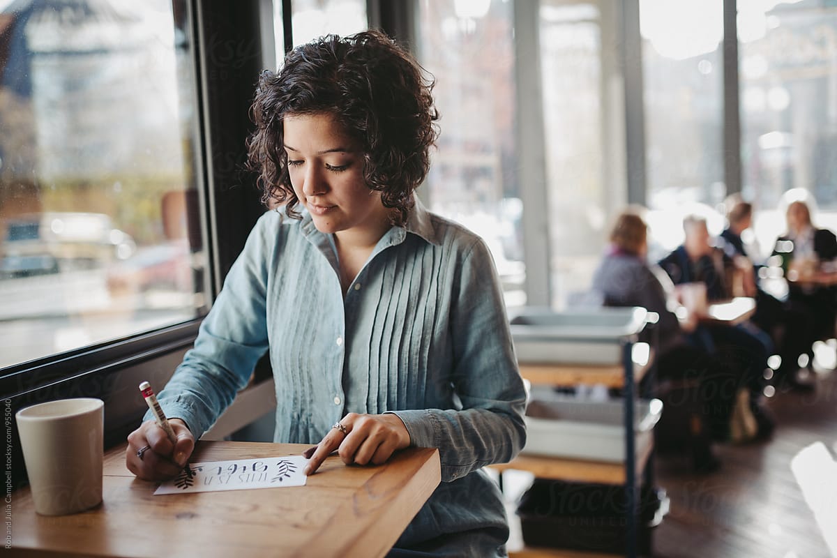 Young woman drawing letter art in coffee shop