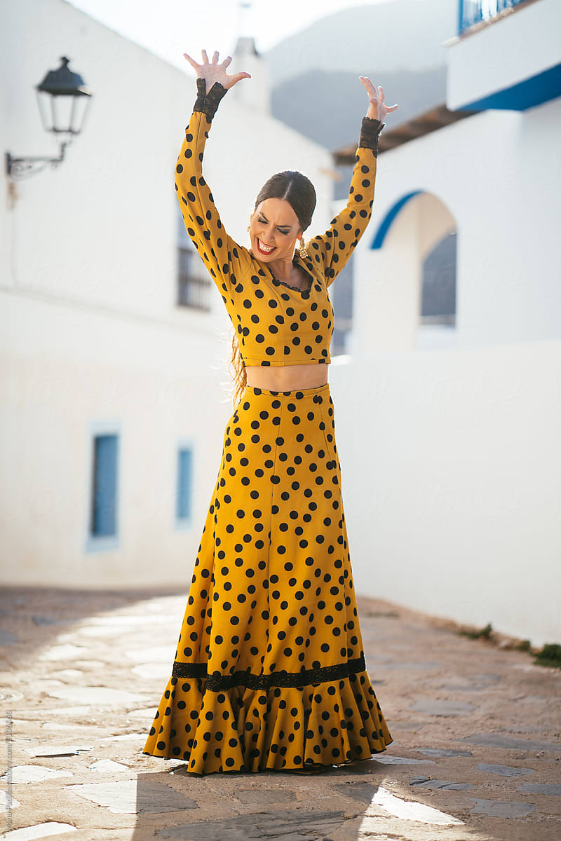 Joyful Hispanic woman in dress with raised arms