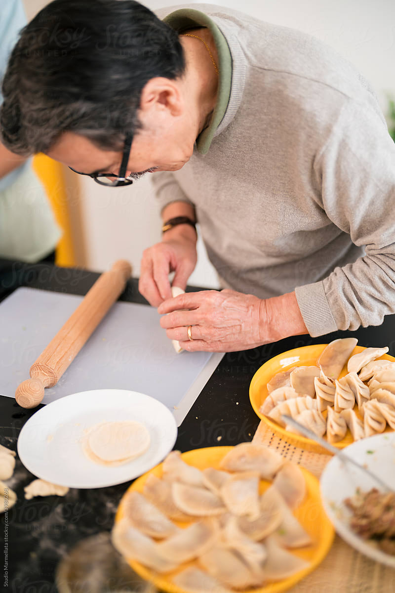 Japanese man preparing gyoza from raw dough in kitchen