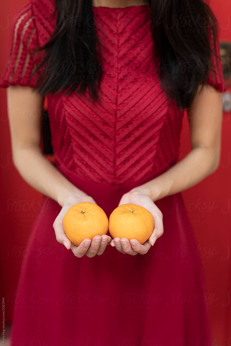 Chinese New Year, a pair of oranges held by a woman wearing a red dress