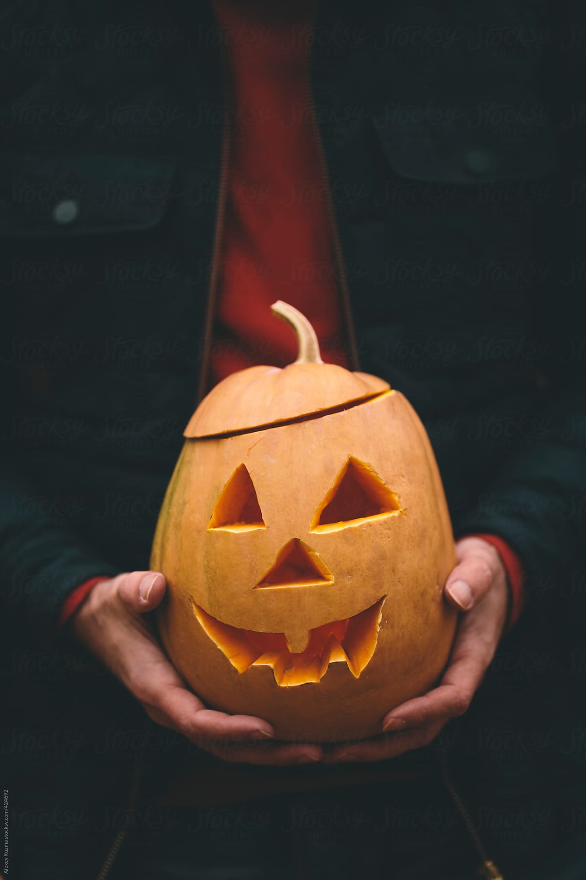 man holding Halloween Jack O\' Lantern pumpkin