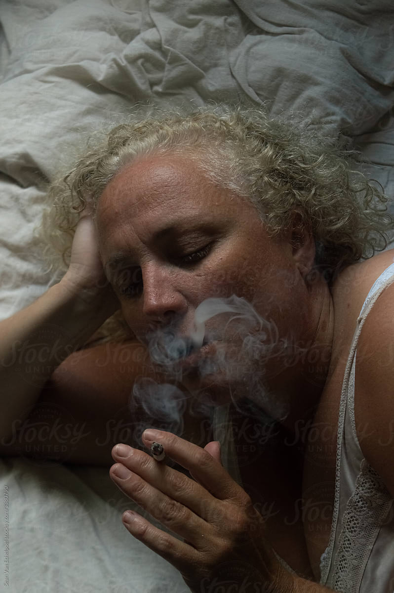 Woman smoking a cigarette in bed