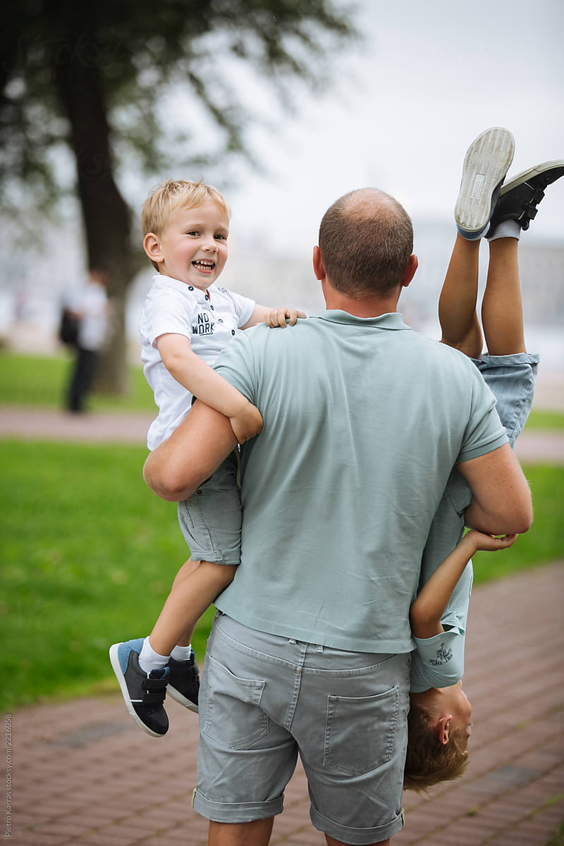 Man holding kids upside down in park