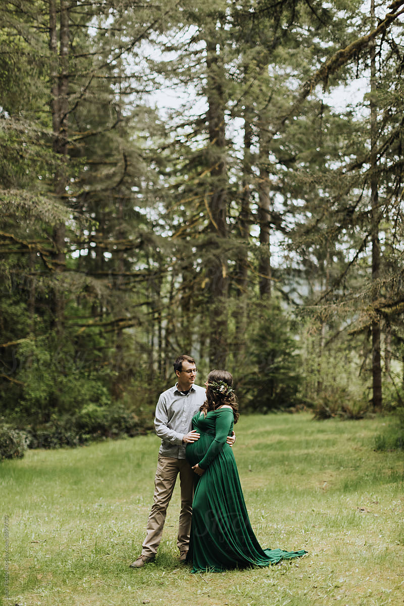 A Man and Woman Embrace a Pregnant Belly in the Forest