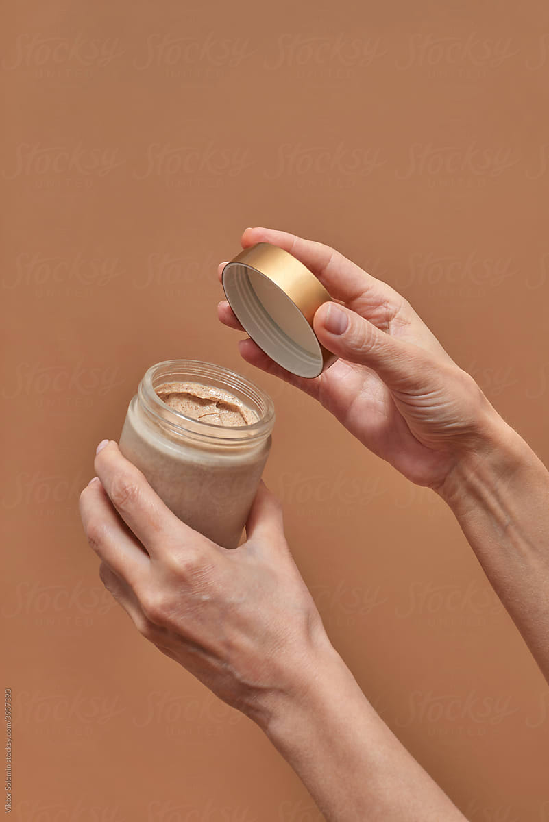 Crop female opening jar with cosmetic product
